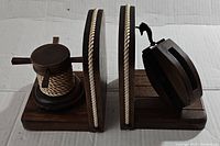 Pair of dark stained wooden nautical bookends shown from above on a white background. One with coiled rope on posts, the other with attached pulley block.