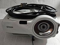 Front view of Epson projector showing lens and attached cables.