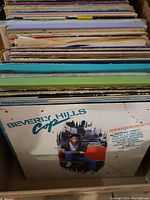 Side view showing multiple vinyl records stacked with Beverly Hills Cop album on top