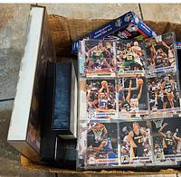 Basketball trading cards visible in protective sleeves showing various players from 90s NBA teams along with boxed memorabilia on the side.