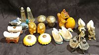 Full group view of 16 vintage salt and pepper shakers in themed ceramic and glass styles