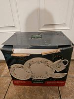 Box showing Pfaltzgraff Winterberry dinnerware set with partial illustration of the plates and cups included.