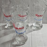 Four vintage Hamms Beer glasses grouped together showing red and blue logo text.
