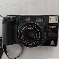 Front view of vintage Minolta Freedom Action Zoom 90 camera showing lens, flash, and autofocus features.
