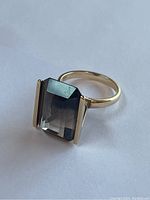 Front three-quarter view of ring showing emerald-cut smoky topaz and gold band