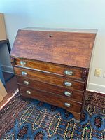Full frontal view of the antique desk showing the closed drop front and four drawers with metal cup pull handles.