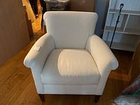 Front view of ivory fabric armchair showing overall design and wooden legs.