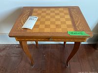 Front view of square wooden game table with chessboard inlay and decorative gold trim on tabletop edges