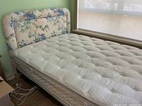 Full side view of double bed with floral padded headboard, mattress, and boxspring