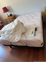 Mattress on black adjustable base with bedside tables visible