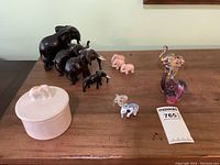 All elephant figurines and pottery jar displayed on wooden table