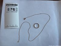 Photo showing the two items side by side: a gold ring and a thin gold chain on a white background with auction label.