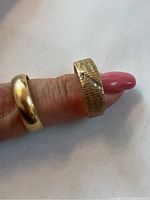 Two yellow gold bands worn on finger showing front profiles