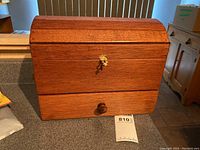 Closed view of handcrafted wooden storage box with dome-shaped hinged lid and small lock.