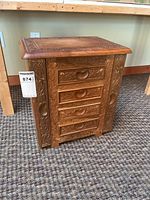 Front view of the carved wood jewelry chest showing intricate floral and leaf carvings with four drawers and heart-shaped carved wooden handles.