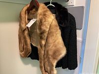 Persian lamb jacket with mink stole draped over on hanger, showing textures and colors
