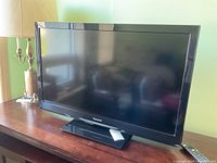 Panasonic flat screen TV on wooden furniture, showing front and side view.