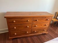 Front view of the pine wood dresser showing 6 drawers with round wooden knobs and natural pine finish.
