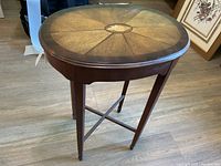 Full view of small occasional table showing oval shape, four legs, and crossbar stretcher.