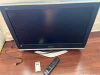 Front view of Panasonic VIERA LCD TV with power cord and remote control on wooden floor