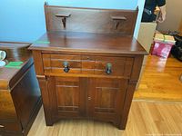 Front view of wooden wash stand showing drawer, cabinet doors, and backsplash with shelves.