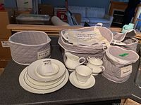 Complete view of Wedgwood Silver Ermine china laid out with storage bags, showing various plates, cream pitcher, sugar bowl with lid, cup and saucer.