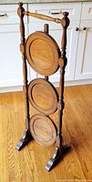 Front view of the vintage 3-tier folding walnut pie stand showing three circular tiers supported by turned wooden spindles.