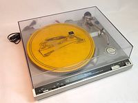 Technics SL-220 turntable with yellow slip mat inside Technics dust cover, showing front panel and controls