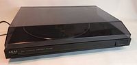 AKAI AP-A150 turntable closed with dark translucent dust cover visible from front side angle