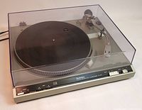 Front and side view of Technics SL-210 turntable with closed dust cover showing control switches and tonearm.