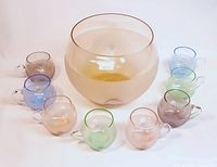 9-piece Luigi Bormioli punch set arranged with large frosted punch bowl in center, surrounded by 8 handle glasses in blue, green, pink, and purple pastel colors.