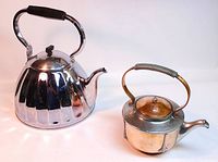 View showing both large Soviet nickel-plated kettle with fluted body and smaller Art Nouveau copper kettle with pewter accents and coiled handle.