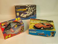 Three vintage remote control cars in original boxes: Radio Shack Lamborghini Countach with box, Radio Shack Porsche 928 with box, and Front Runners Jeff Gordon #24 car in box.