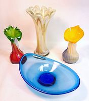 Four colorful art glass pieces shown together: two flower vases with fluted tops, one finger vase, and one blue glass dish.