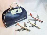 Dark blue and white vinyl Air Canada travel bag and three aviation promotional model airplanes on white background