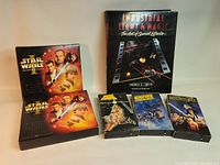Photo of the complete lot showing the hardcover book, three VHS tapes, and two Phantom Menace collector boxes with visible content.