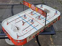 Full view angled photo of the electric Canadian hockey table-top game showing rink markings, players, nets, and scoreboard