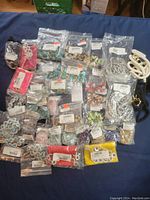 Overview of assorted costume jewelry pieces in sealed plastic bags spread on a surface, showing variety and quantity.