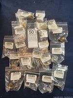 21 costume rings individually bagged, laid out on dark fabric background showing variety of styles and finishes.