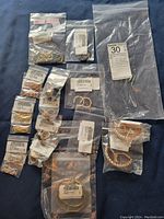 Top view showing assortment of individually bagged silver plated and gold plated jewelry including chains, rings, bracelets, and earrings.