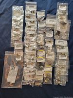 Overall view of 50 individually bagged sterling silver plated earrings laid out in rows showing variety of designs and gemstone colors.