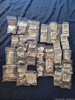 Lot of 53 assorted sterling silver plate earrings individually bagged with tags and barcodes, displayed on a fabric surface.