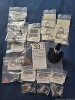Overview of all 15 sterling silver plated rings, individually bagged with labels, some displayed on ring holders.