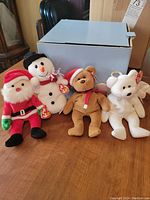 Lot overview showing all four Beanie Babies including Santa, Snowball, Halo, and 1997 Teddy Style 4200 bear next to a blue box