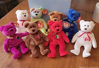 Front view of all 8 Beanie Babies showing different colors and country emblems.