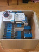 Box full of multiple retail boxed Fantasy Qi wireless chargers with blue and white packaging.