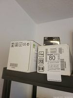 Photo of HP LaserJet toner cartridge boxes stacked on a shelf, showing model and recycling information on the boxes.