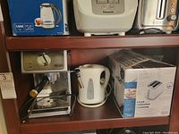 Shelf with espresso machine, electric kettle, and boxed toaster