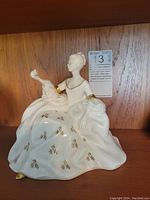 Front view showing the figurine's detailed dress with gold floral patterns and gold accents on sleeves and shoes.