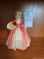 Front view of Royal Doulton Janet figurine showing pink dress, white apron, bonnet, and basket of flowers.